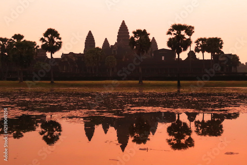 Picturesque view onto the temple of Angkor Wat before sunrise, its silhouette and the pink sky reflect on the water, lake, pond, Siem Reap, Cambodia photo