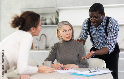 Couple man and woman discussing testament with elderly woman in kitchen at home