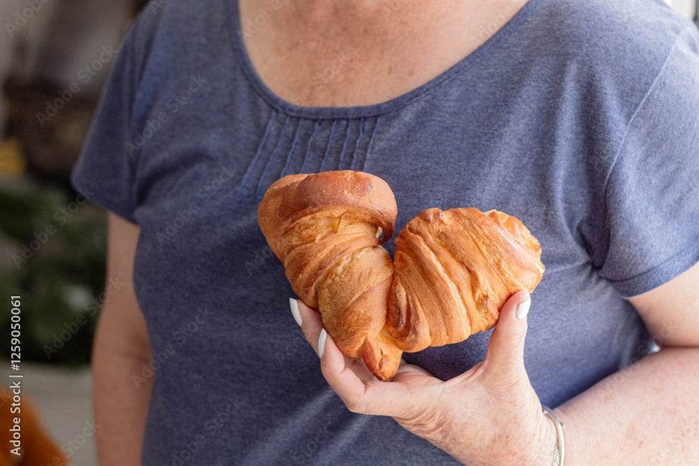 Unrecognizable woman holding over her heart two heart-shaped bread joined together. Traditional artisanal Colombian butter bread. Concept of love for gastronomy Unrecognizable woman holding over her heart two heart-shaped bread joined together. Traditional artisanal Colombian butter bread. Concept of love for gastronomy