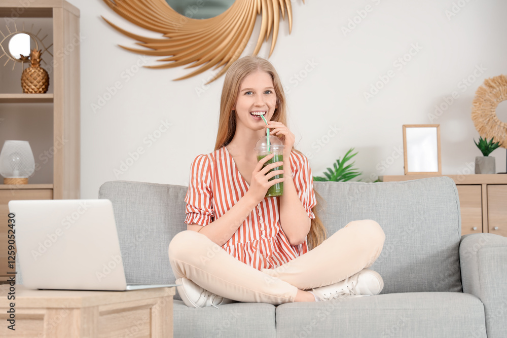 Young woman with healthy smoothie and laptop sitting on sofa at home Young woman with healthy smoothie and laptop sitting on sofa at home