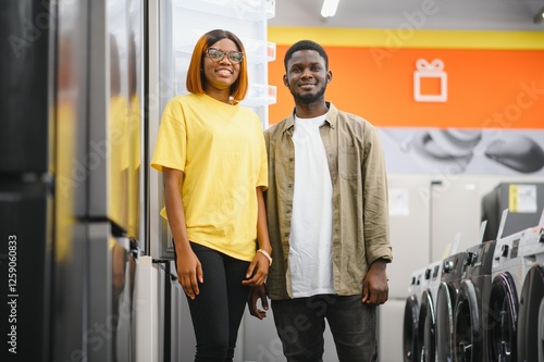 Young african american man and woman are choosing a fridge in an appliance store. photo