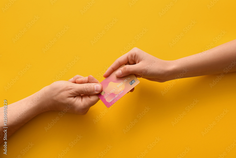 Couple holding credit card on yellow background, top view Couple holding credit card on yellow background, top view