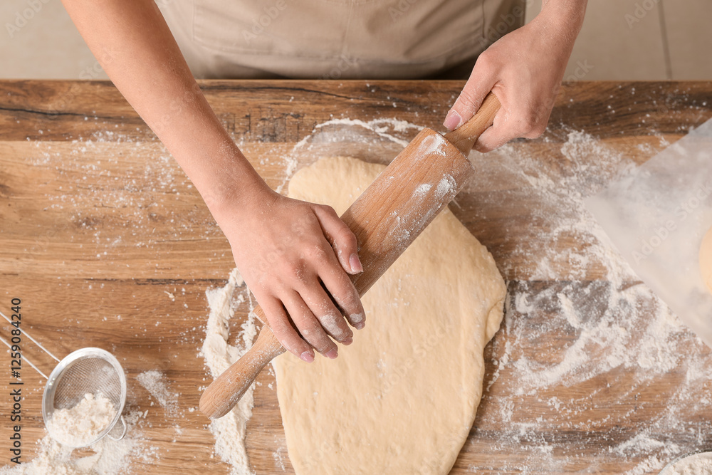 Woman rolling out fresh dough on table, top view Woman rolling out fresh dough on table, top view