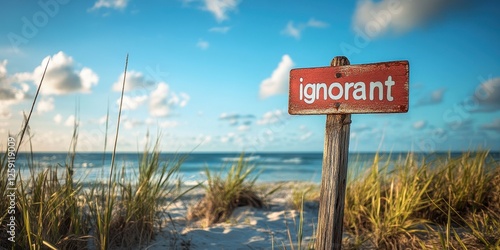A Vibrant Coastal Scene with a Red Wooden Sign Displaying the Word "Ignorant" on a Sandy Beach Surrounded by Grass and Overlooking the Ocean During a Bright Sunny Day
