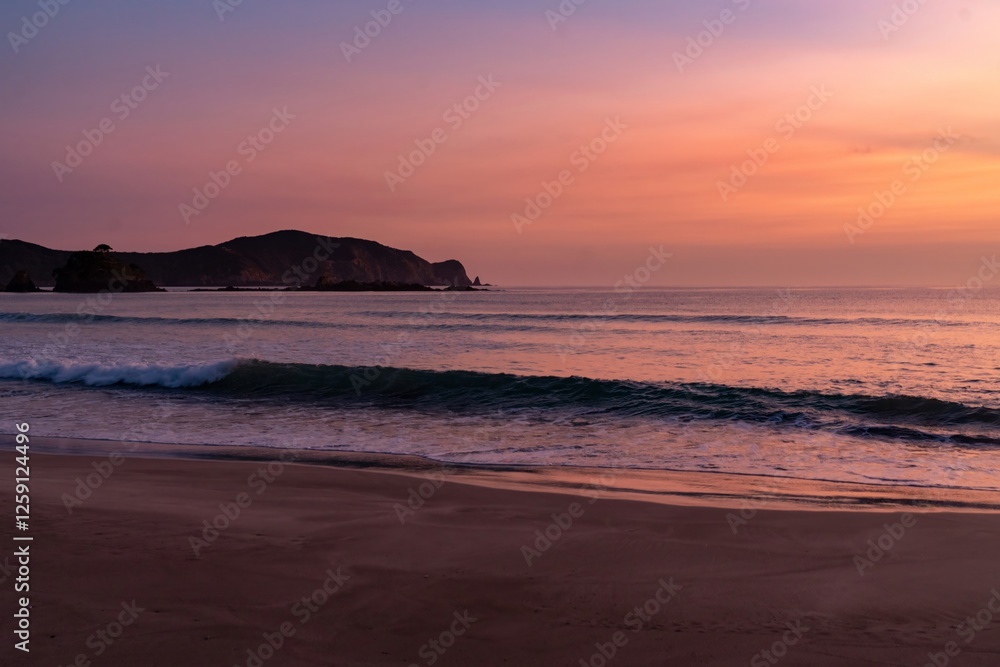 Sunrise over a tranquil beach. Gentle waves wash ashore as the sky transitions to a beautiful pink hue. Peaceful morning. Elliot Bay, Rawhiti, Northland, New Zealand Sunrise over a tranquil beach. Gentle waves wash ashore as the sky transitions to a beautiful pink hue. Peaceful morning. Elliot Bay, Rawhiti, Northland, New Zealand
