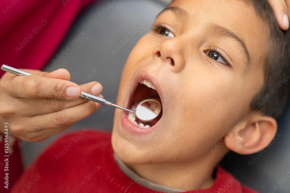 Dentist examining teeth of young boy with dental mirror Dentist examining teeth of young boy with dental mirror