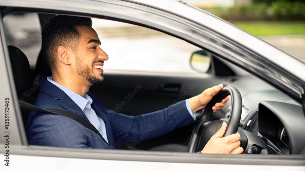 Happy middle eastern young businessman driving new auto, going to office, shot from outside, side view. Handsome successful arab guy manager going home after good day, looking at road and smiling Happy middle eastern young businessman driving new auto, going to office, shot from outside, side view. Handsome successful arab guy manager going home after good day, looking at road and smiling