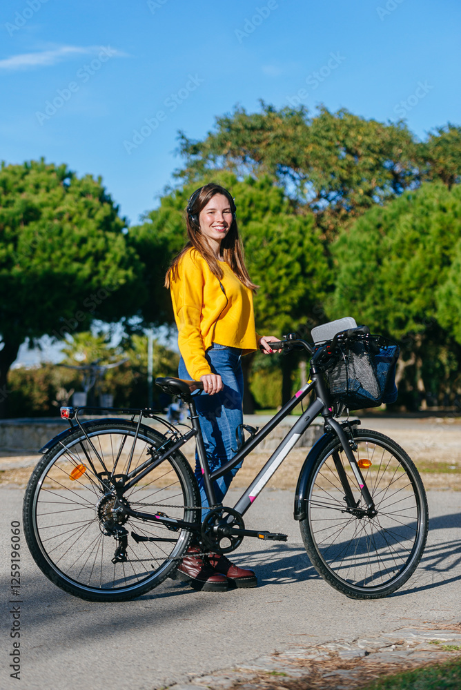 Obraz premium Woman with bike and headphones in the park.