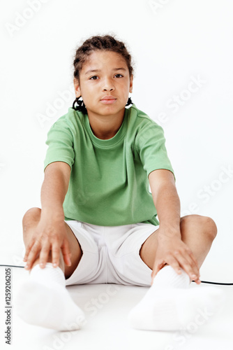 Young boy in green shirt sitting on floor with hands on knees, deep in thought and contemplation photo