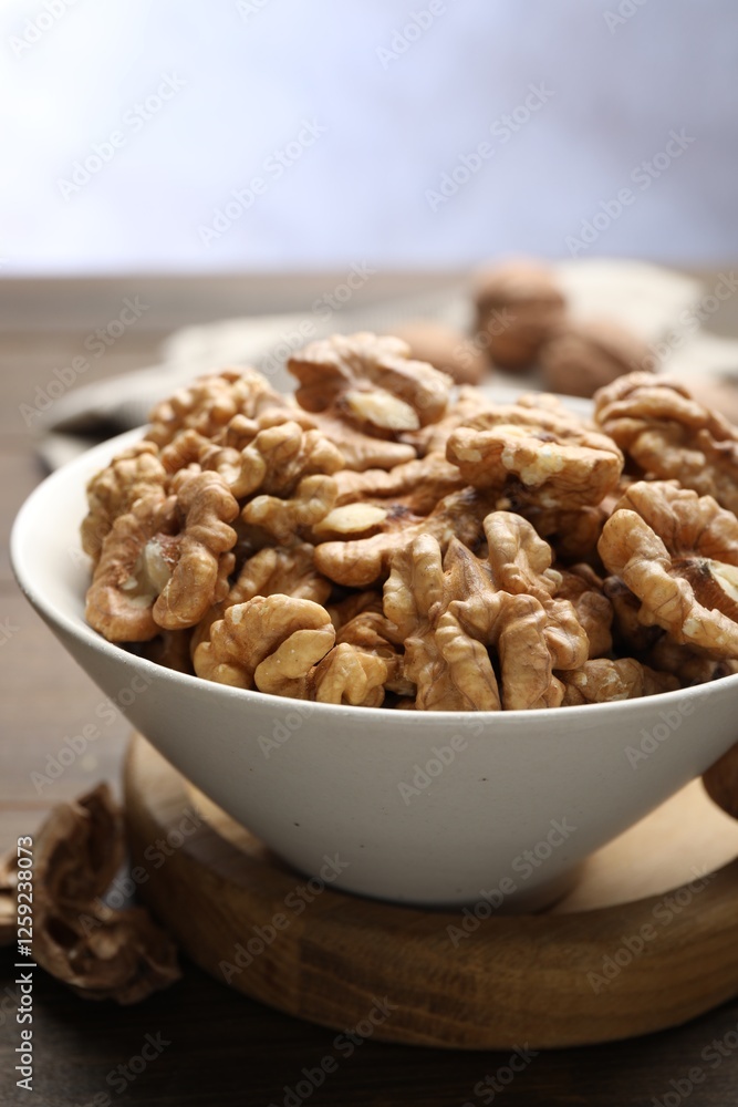 Peeled walnuts in bowl on table against light background, closeup Peeled walnuts in bowl on table against light background, closeup