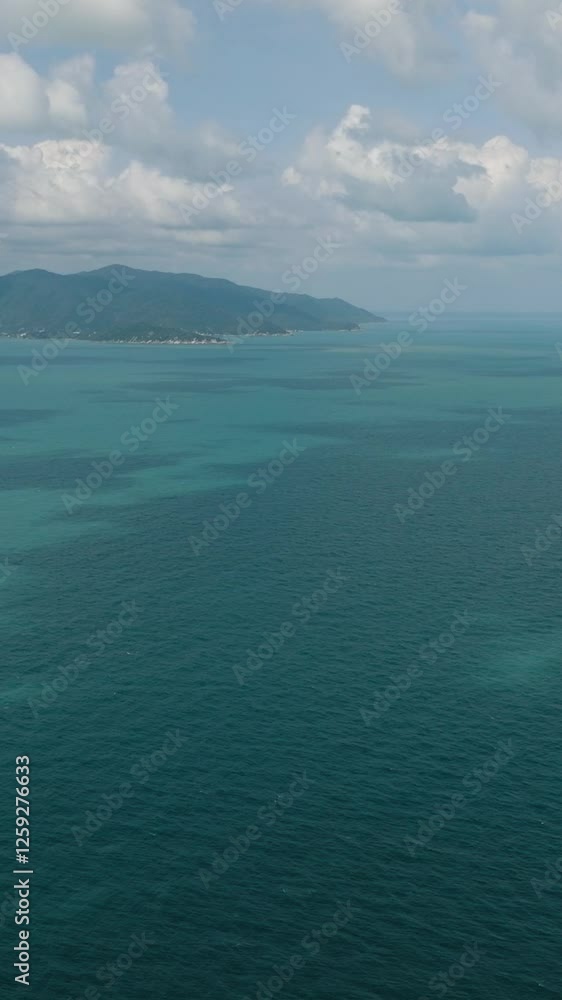 Turquoise sea with a small rocky island under a bright cloudy sky. Ko Samui, Thailand. Turquoise sea with a small rocky island under a bright cloudy sky. Ko Samui, Thailand.