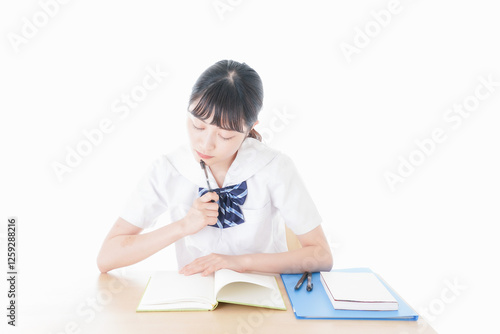 机で勉強をする制服姿の女子学生 photo