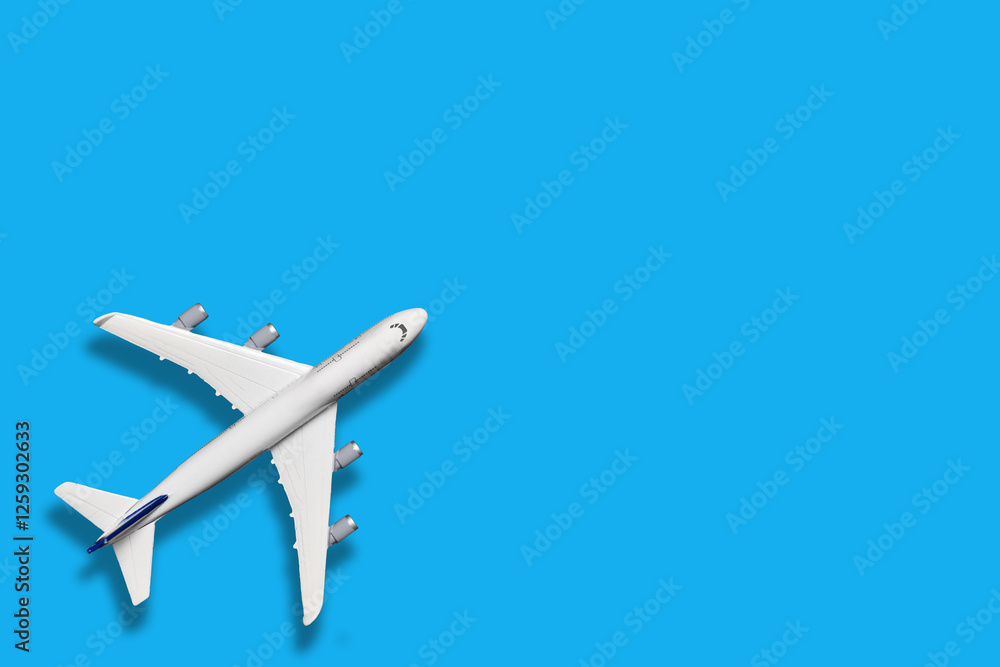 Miniature model airplane on blue color background, flat lay design