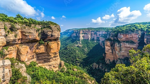 Majestic canyon landscape with lush greenery under a bright blue sky and fluffy clouds