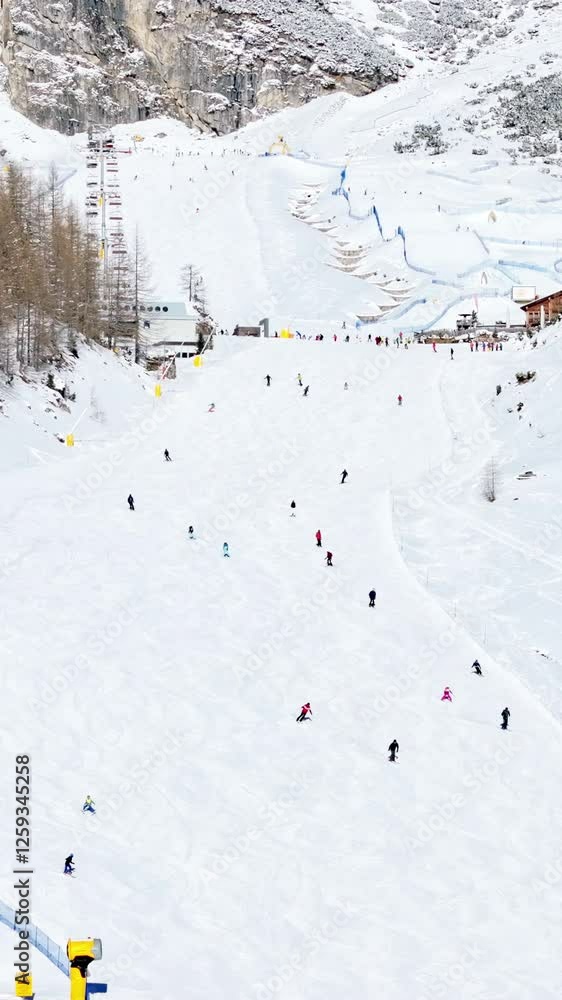 Aerial drone view of people skiing in Colfosco in South Tyrol, Dolomites, Northern Italy. Vertical Aerial drone view of people skiing in Colfosco in South Tyrol, Dolomites, Northern Italy. Vertical