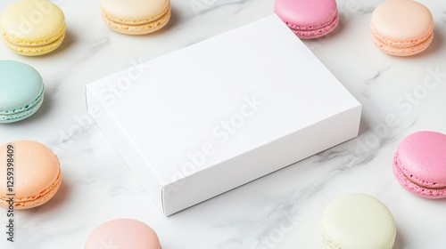 Pastel-colored macarons arranged around a blank white box on a marble surface.  Sweet treat mock-up.