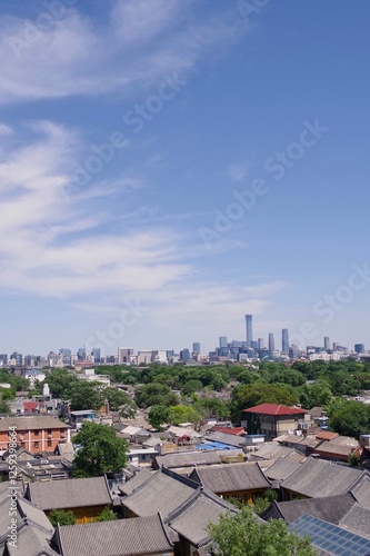 Wide view of gray roofed traditional hutong buildings and skyscrapers in background