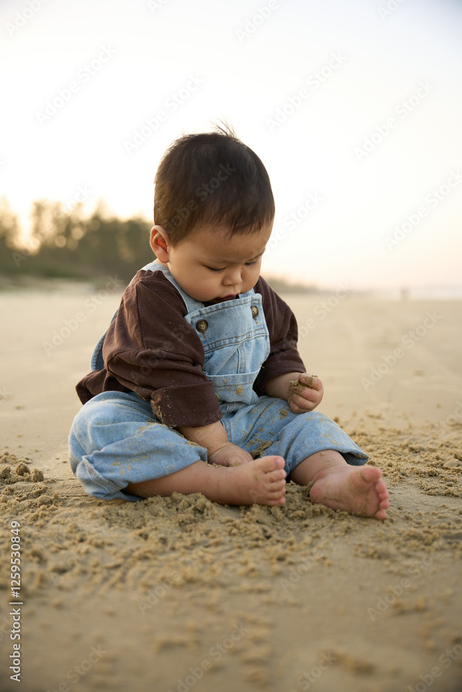 there is a baby sitting on the sand on the beach there is a baby sitting on the sand on the beach