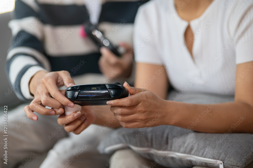 A close-up of two friends play a video game with joysticks on the sofa. A close-up of two friends play a video game with joysticks on the sofa.