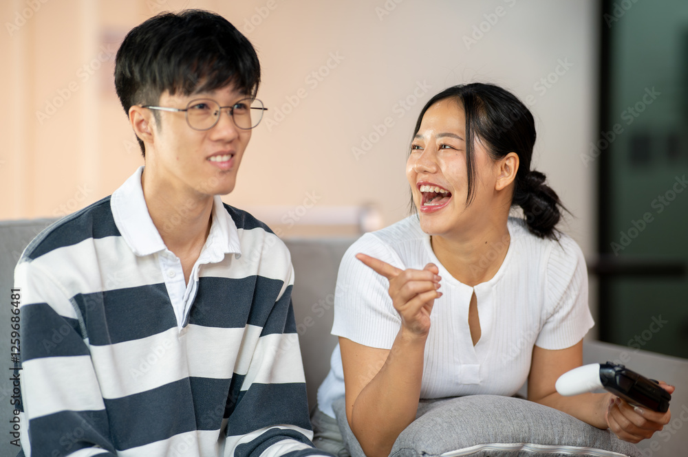 Two cheerful and joyful Asian friends are enjoy playing a video game on the sofa together. Two cheerful and joyful Asian friends are enjoy playing a video game on the sofa together.
