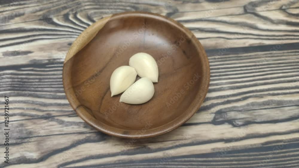 Closeup of Garlic or Allium sativum on wooden plate on wooden table Closeup of Garlic or Allium sativum on wooden plate on wooden table