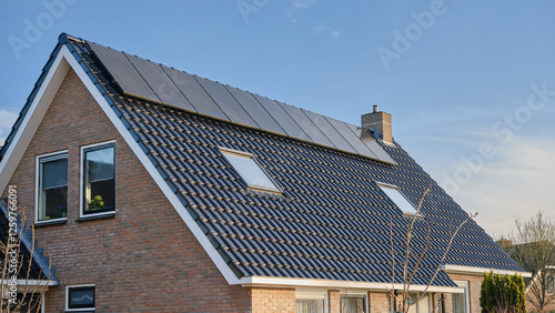 Modern house with solar panels on tiled roof for renewable energy, Netherlands, under a clear blue autumn sky