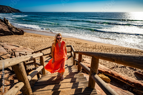 Beautiful woman walking up stairs from sunny beach -Portugal, Algarve, Amado praia	