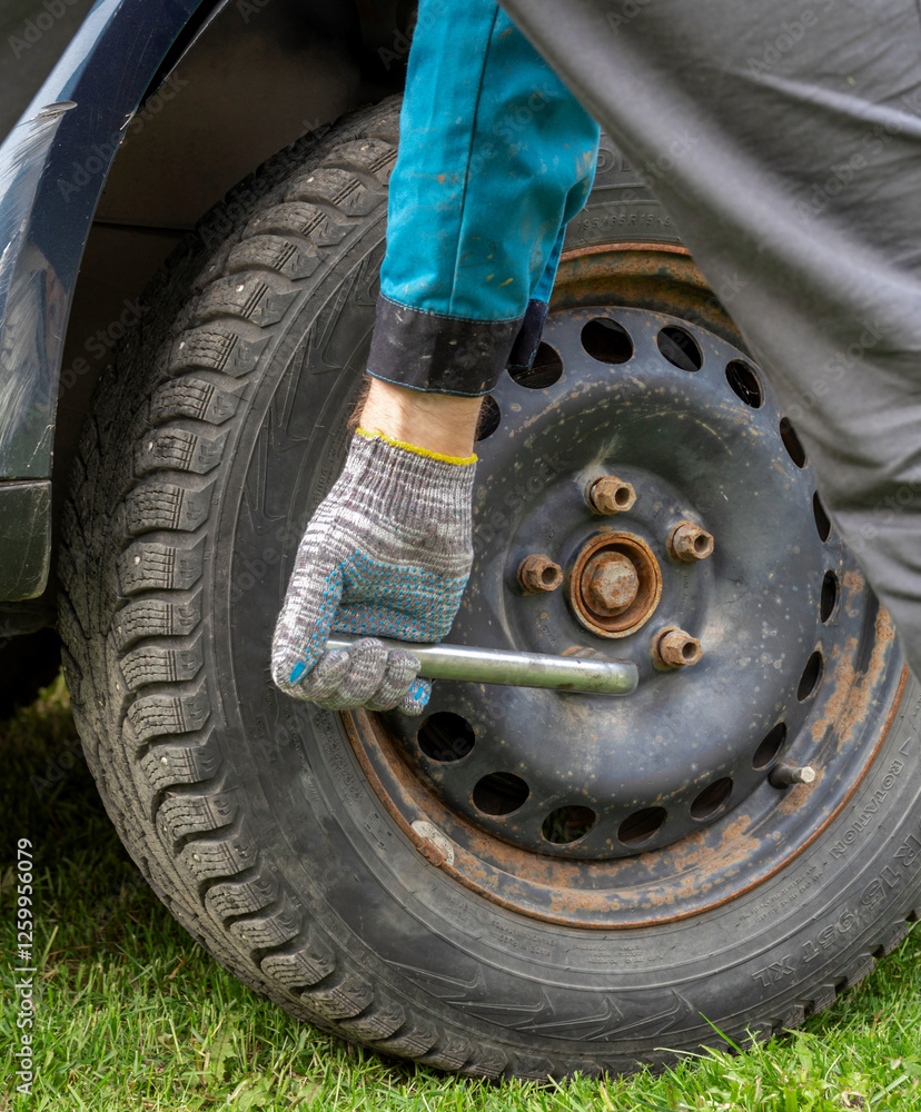 Man is working on a car tire with a wrench Man is working on a car tire with a wrench
