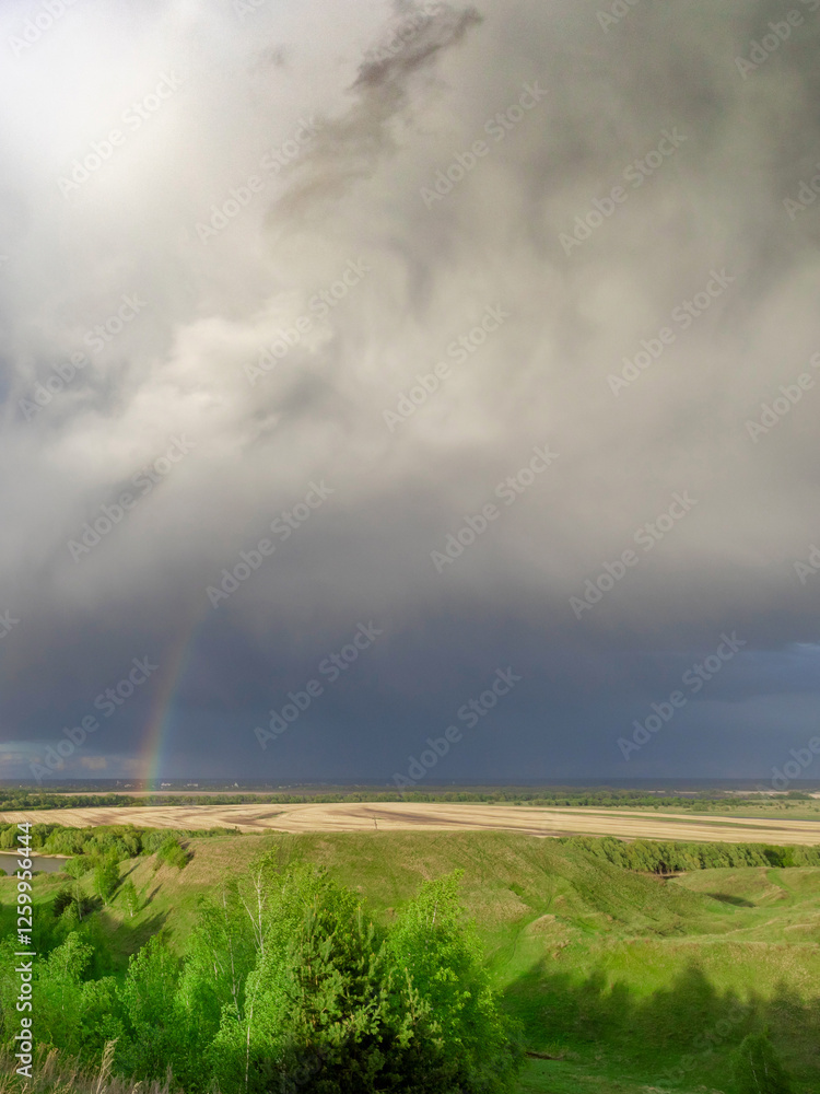 Rainbow is seen in the sky above a field Rainbow is seen in the sky above a field