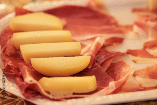 fette di scamorza affumicata e prosciutto crudo su un piatto bianco