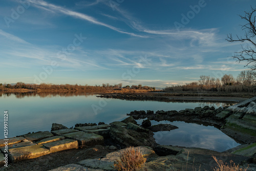 ambiente naturale fluviale tra la foce del fiume Isonzo ed il mare Adriatico, nell'Italia nord-orientale, di pomeriggio, con un cielo sereno, velato da nuvole leggere, in inverno photo