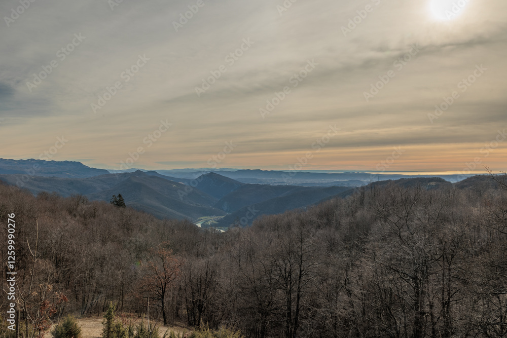 panoramica con vista su un ambiente naturale tra le alte colline e le montagne della Slovenia occidentale, vicino al confine Italiano, di pomeriggio, con cielo leggermente nuvoloso, in inverno