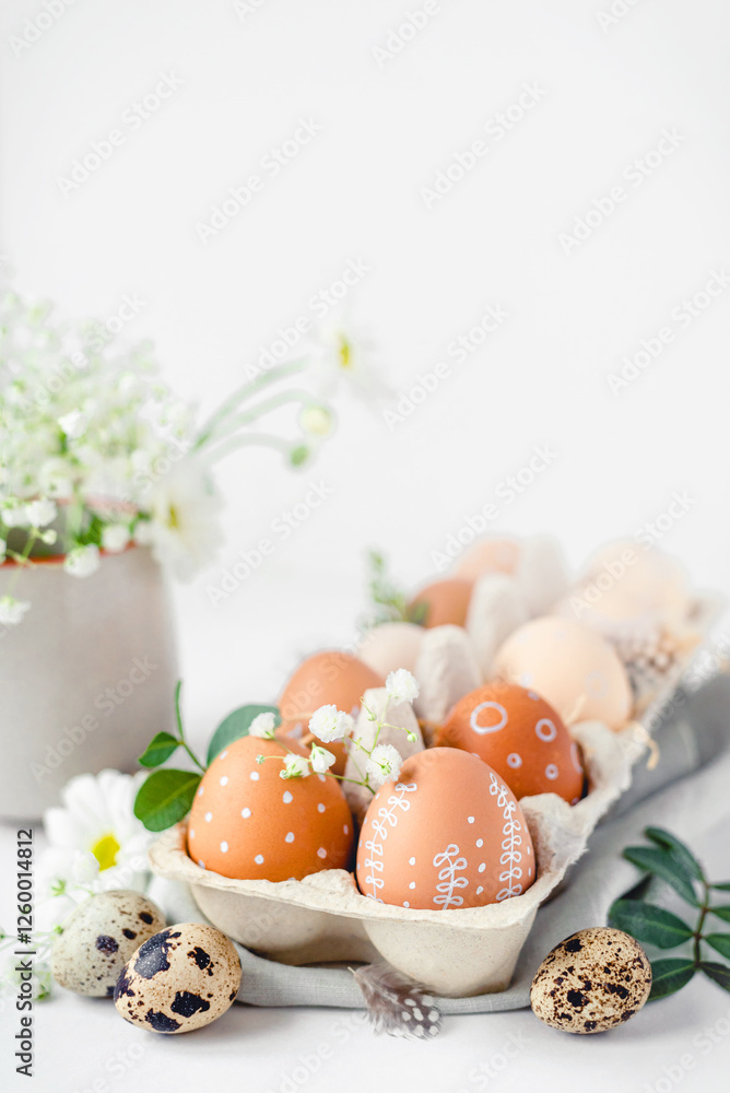 A delicate Easter background with hand-painted eggs in a box on a white table. Easter composition with flowers and feathers A delicate Easter background with hand-painted eggs in a box on a white table. Easter composition with flowers and feathers