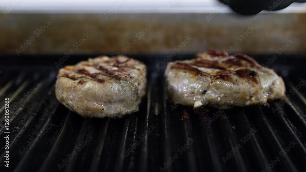 Close-up of two pieces of meat cooking on the grill to a golden crust. The concept focuses on the grilling process, highlighting the appetizing appearance and perfect texture of the grilled meat. Close-up of two pieces of meat cooking on the grill to a golden crust. The concept focuses on the grilling process, highlighting the appetizing appearance and perfect texture of the grilled meat.