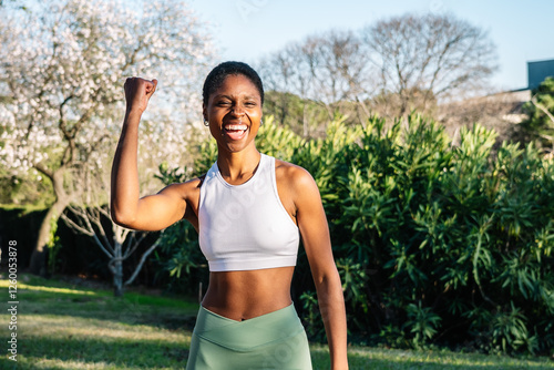Wallpaper Mural Young black woman showing her biceps and celebrating in a park Torontodigital.ca