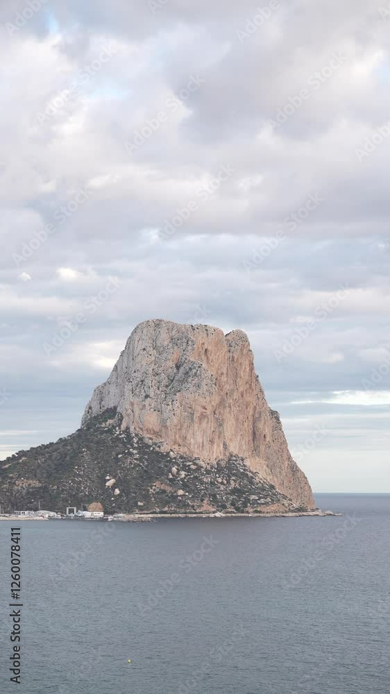 Ifach is in the distance with a cloudy sky. The sky is overcast and the mountain is covered in snow Ifach is in the distance with a cloudy sky. The sky is overcast and the mountain is covered in snow
