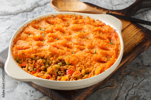 Obraz na płótnie Sweet potato shepherd's pie with ground turkey, green peas, onions, peppers and tomatoes close-up in a baking dish on a wooden board. Horizontal w salonie