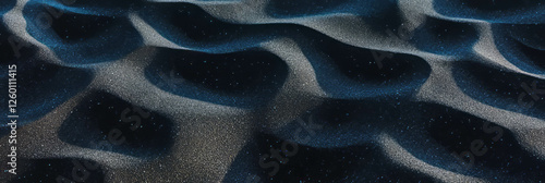 Exploring the soft texture of black sand mixed with fine ash along a coastal area