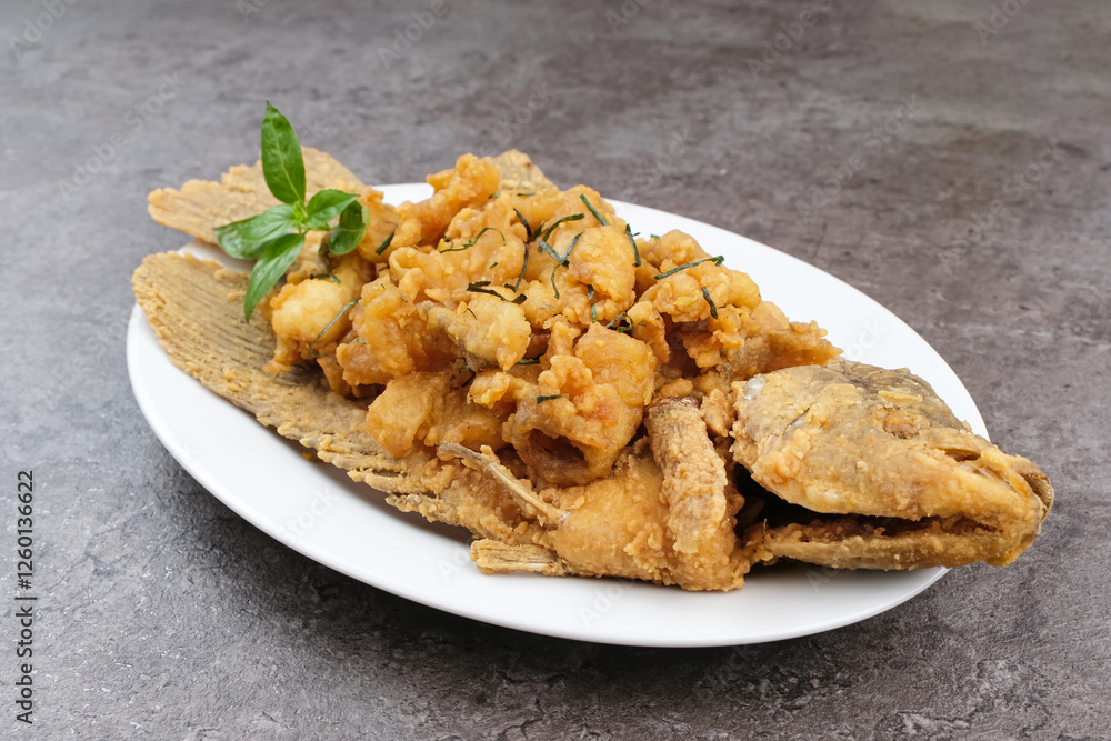 Gurame Saos Telur Asin. Crispy fried gourami fish covered with salted egg sauce. Indonesian food
Gurame Saos Telur Asin. Crispy fried gourami fish covered with salted egg sauce. Indonesian food