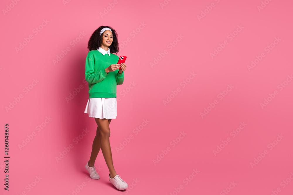 Stylish young woman wearing green sweater and white skirt with red phone against pink background Stylish young woman wearing green sweater and white skirt with red phone against pink background