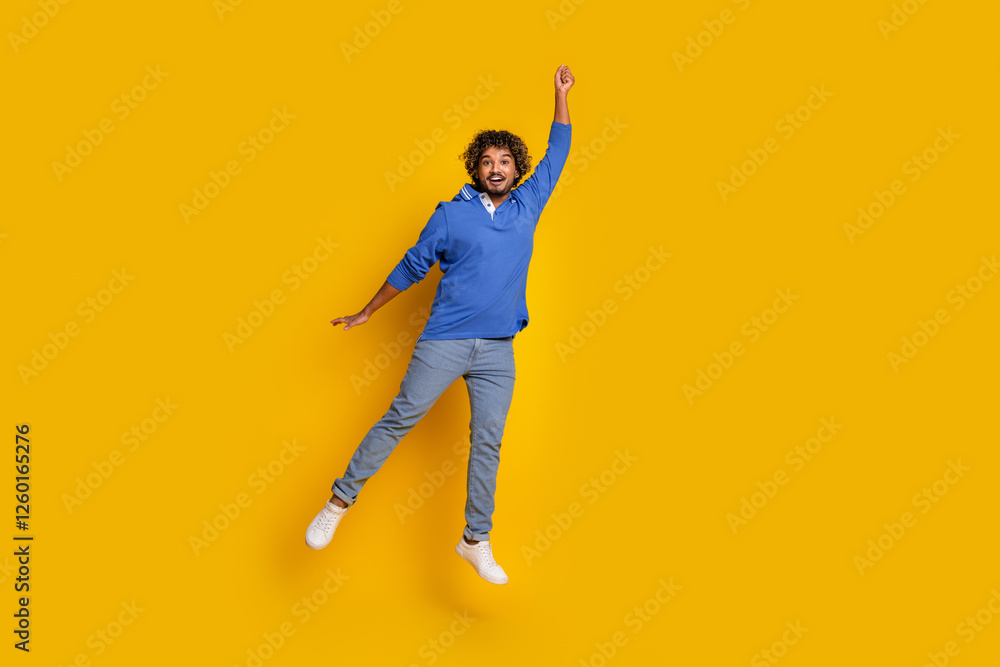 Happy young man jumping with excitement in a cheerful yellow background wearing a blue polo, conveying joy and modern style Happy young man jumping with excitement in a cheerful yellow background wearing a blue polo, conveying joy and modern style