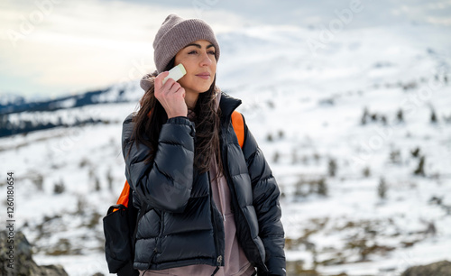 Beautiful Woman applying sun cream in the winter mountain .Spf stick 