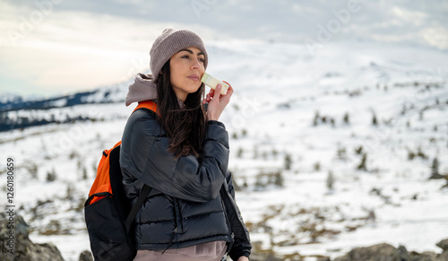 Beautiful Woman applying sun cream in the winter mountain .Spf stick 