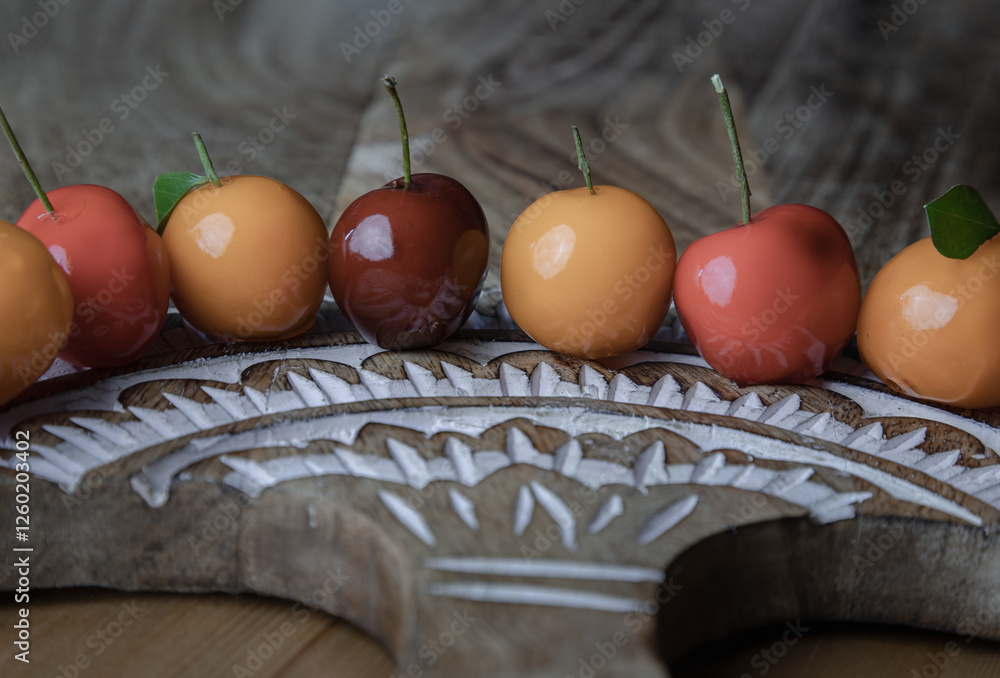 View of Deletable imitation fruits (Kanom look choup) in the shape of fruits has a sweet taste on wood cutting board. Traditional thai sweet treats made from mung beans and coconut milk, and glazed.