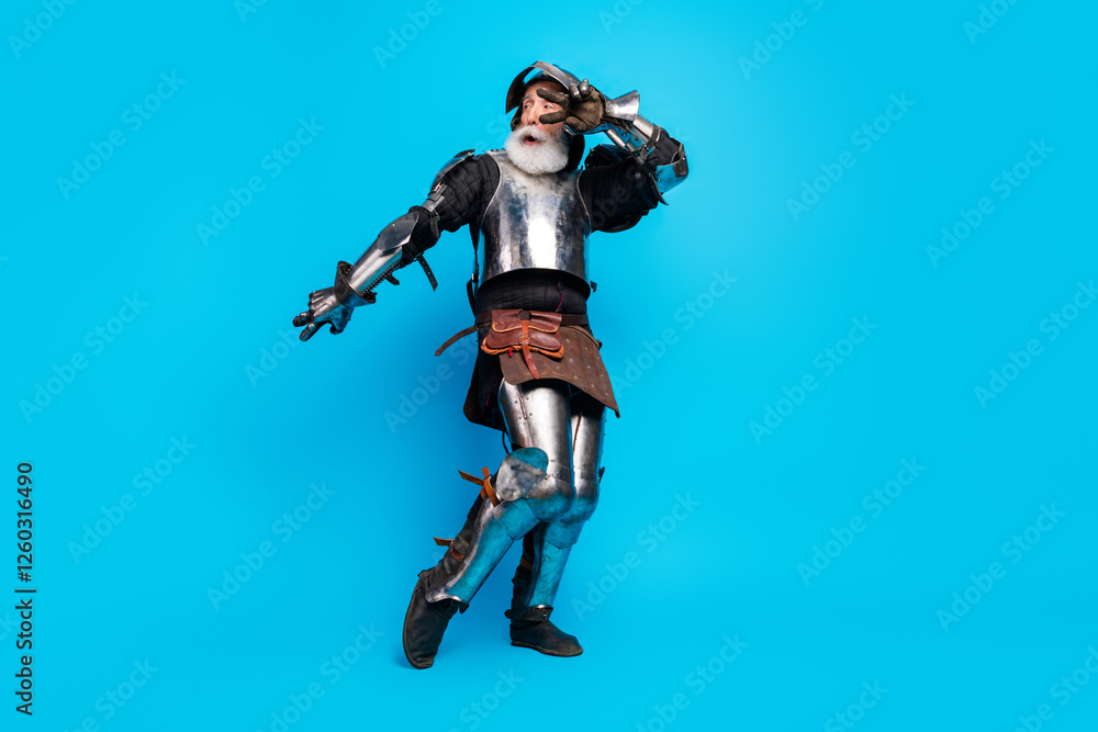 Portrait of an elderly man in medieval knight's armor posing playfully against a bright blue background Portrait of an elderly man in medieval knight's armor posing playfully against a bright blue background