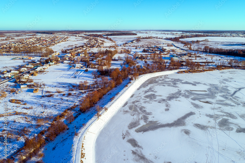 Aerial view of a frozen lake and dam on a sunny winter day