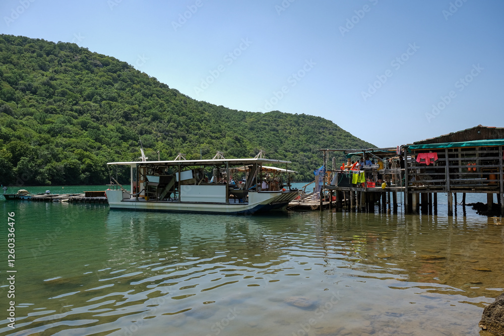 Floating seafood farm with a docked boat in a green bay Floating seafood farm with a docked boat in a green bay