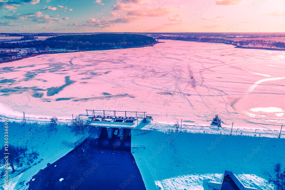 Aerial view of the frozen lake and dam in winter during sunset