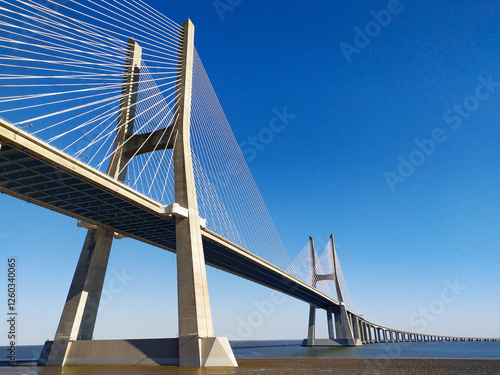 Stunning lowangle view of a cablestayed bridge against a vibrant blue sky.  Perfect for architecture, engineering, travel, and transportation projects. photo