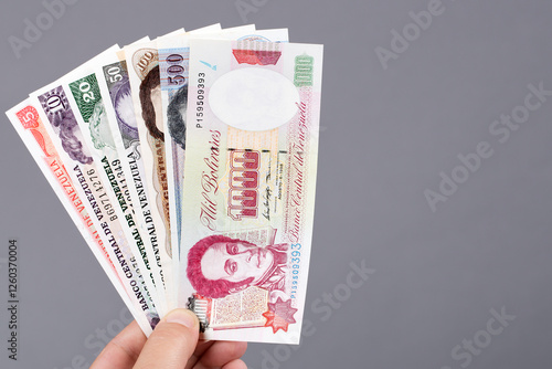 Foto Old Venezuelan bolivar in the hand on a gray background